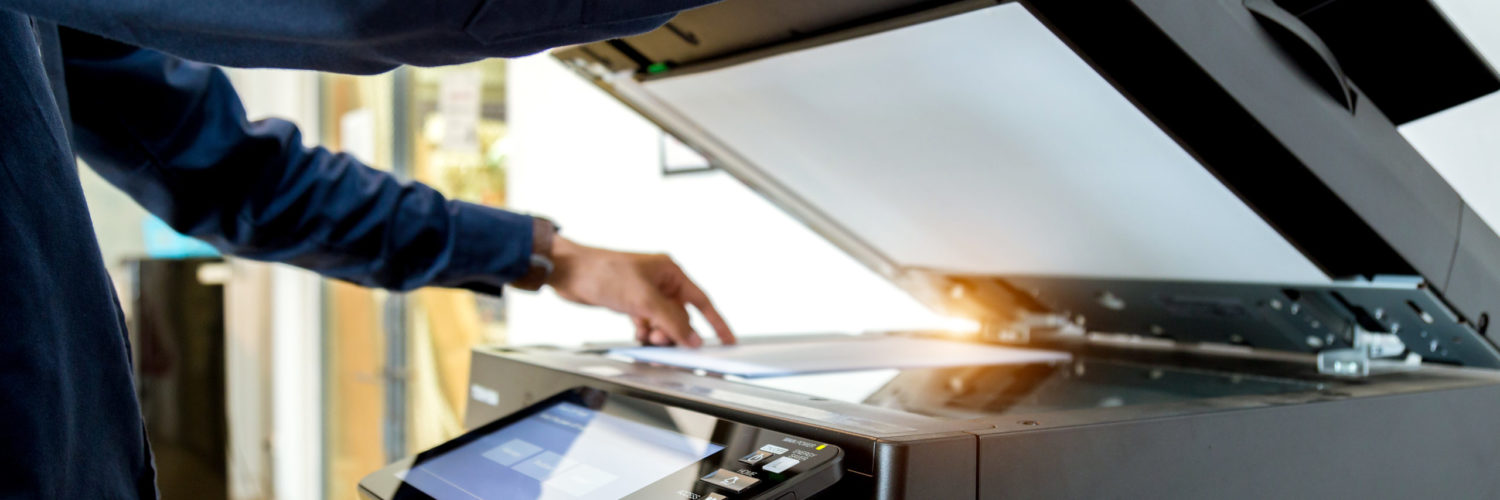 Man holding paper while using scanner